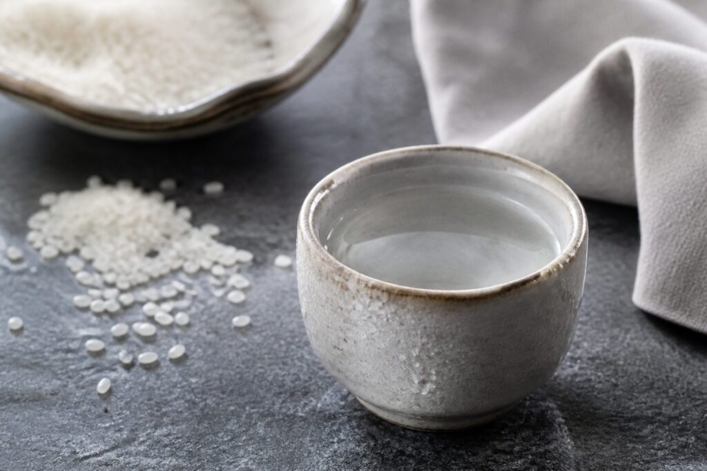 Ceramic sake cup with rice grains on a stone surface